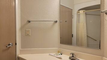 A bathroom with a white sink, a mirror, a towel, and a shower curtain.