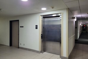 Een lift in een gang met een bordje erboven dat het verdiep aangeeft.