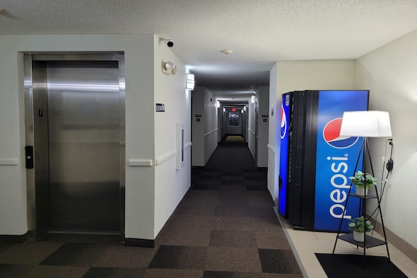 A hotel corridor with an elevator, a Pepsi refrigerator, and a lamp. - Modern Stay 39 Lakeview By OYO Minonk Garden (Minonk)