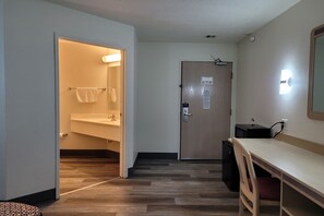 A hotel room with a wooden floor, a desk with a chair, a small trash bin, and a door with a light switch. - Modern Stay 39 Lakeview By OYO Minonk Garden (Minonk)