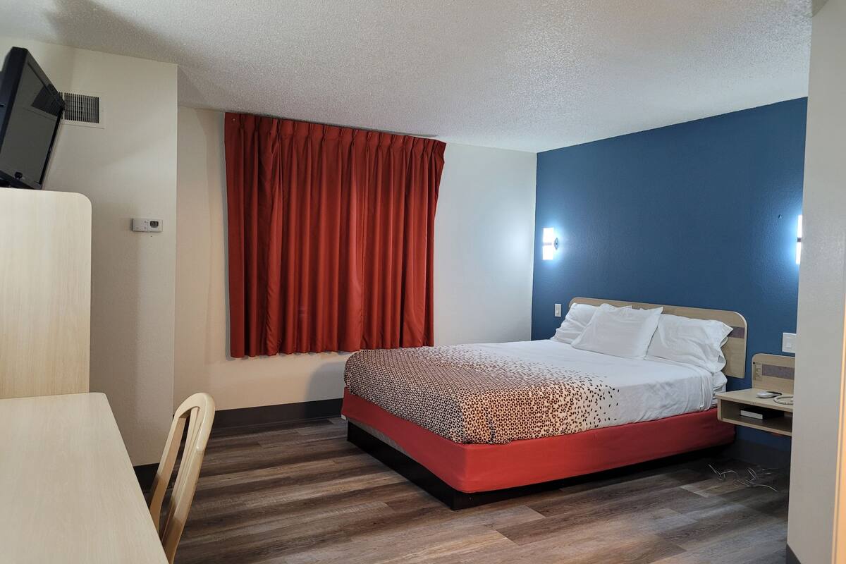 A hotel room with a bed, a desk, and a chair.