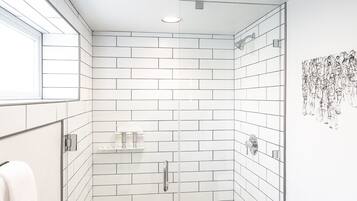 A modern bathroom with white subway tiles, a glass shower enclosure, a toilet, and a towel rack.