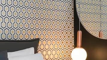 A bed with white and patterned pillows, a dark headboard, and a wall with a geometric pattern.
