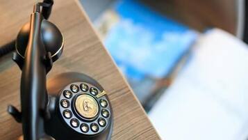 A wooden desk with a black telephone and a book.