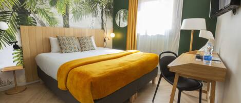 A hotel room with a bed, a desk, a chair, a lamp, a TV, and a large window with curtains.