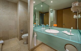 Un baño moderno con tocador de cristal, lavabo blanco y retrete.