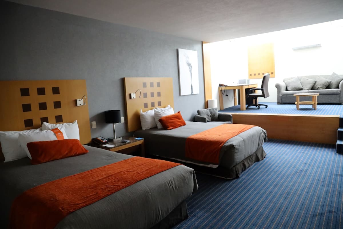 Una habitación de hotel con dos camas, un escritorio, una silla y un sofá.