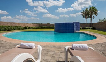 Una piscina al aire libre, sillones reclinables de piscina