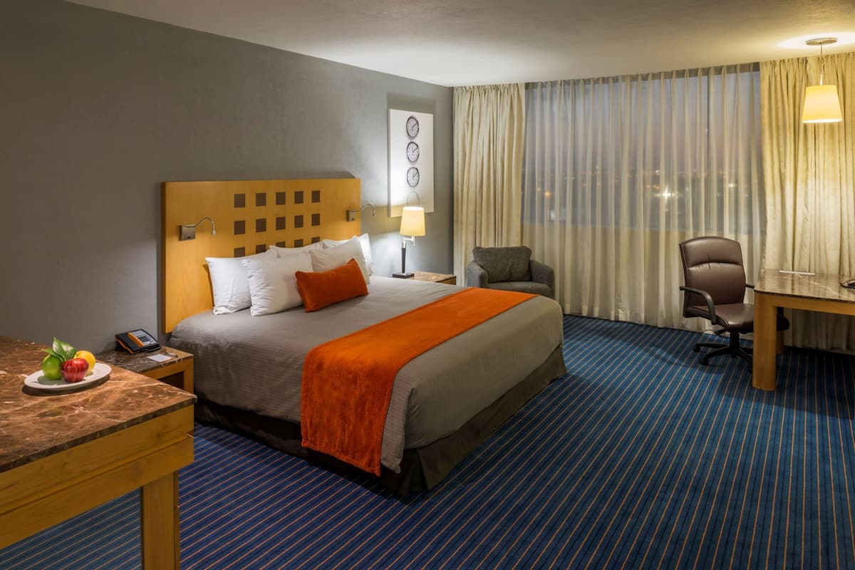 Una habitación de hotel con una cama grande, un escritorio, una silla y una mesa de comedor.