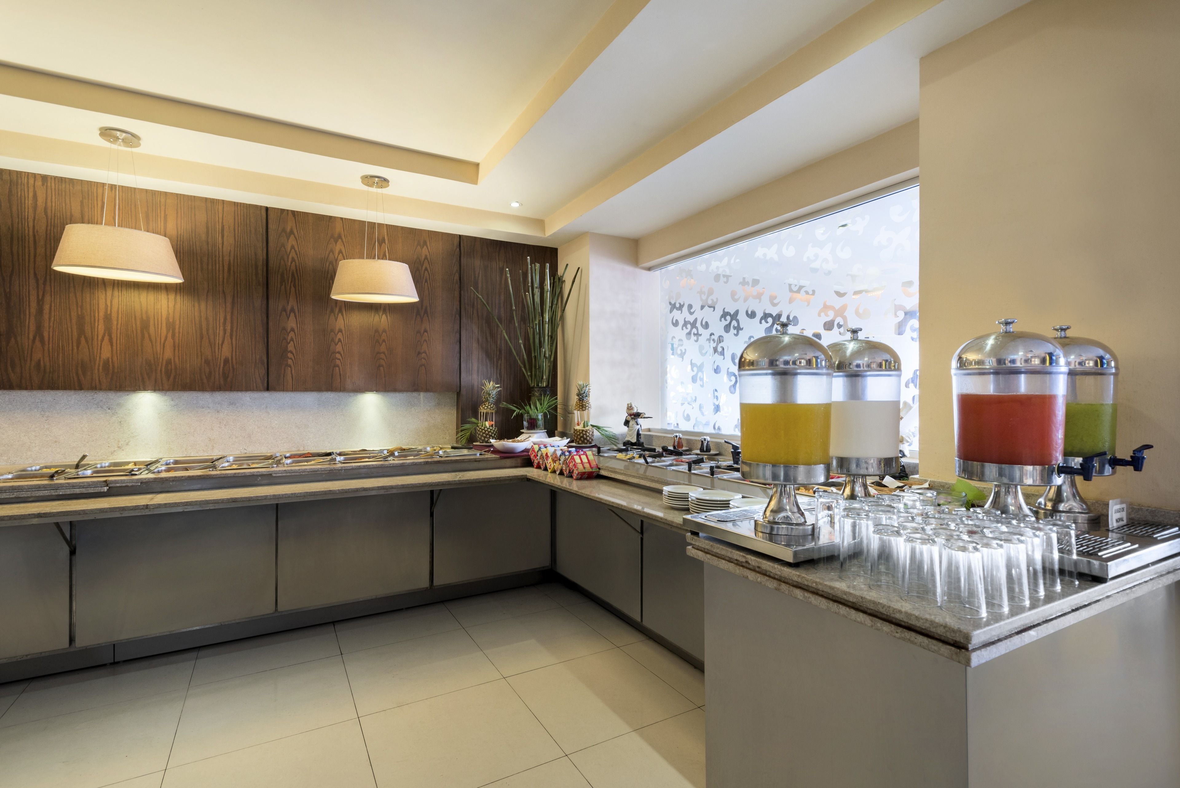 Una cocina moderna con una encimera larga, electrodomésticos de acero inoxidable y un ventanal con vistas decorativas.