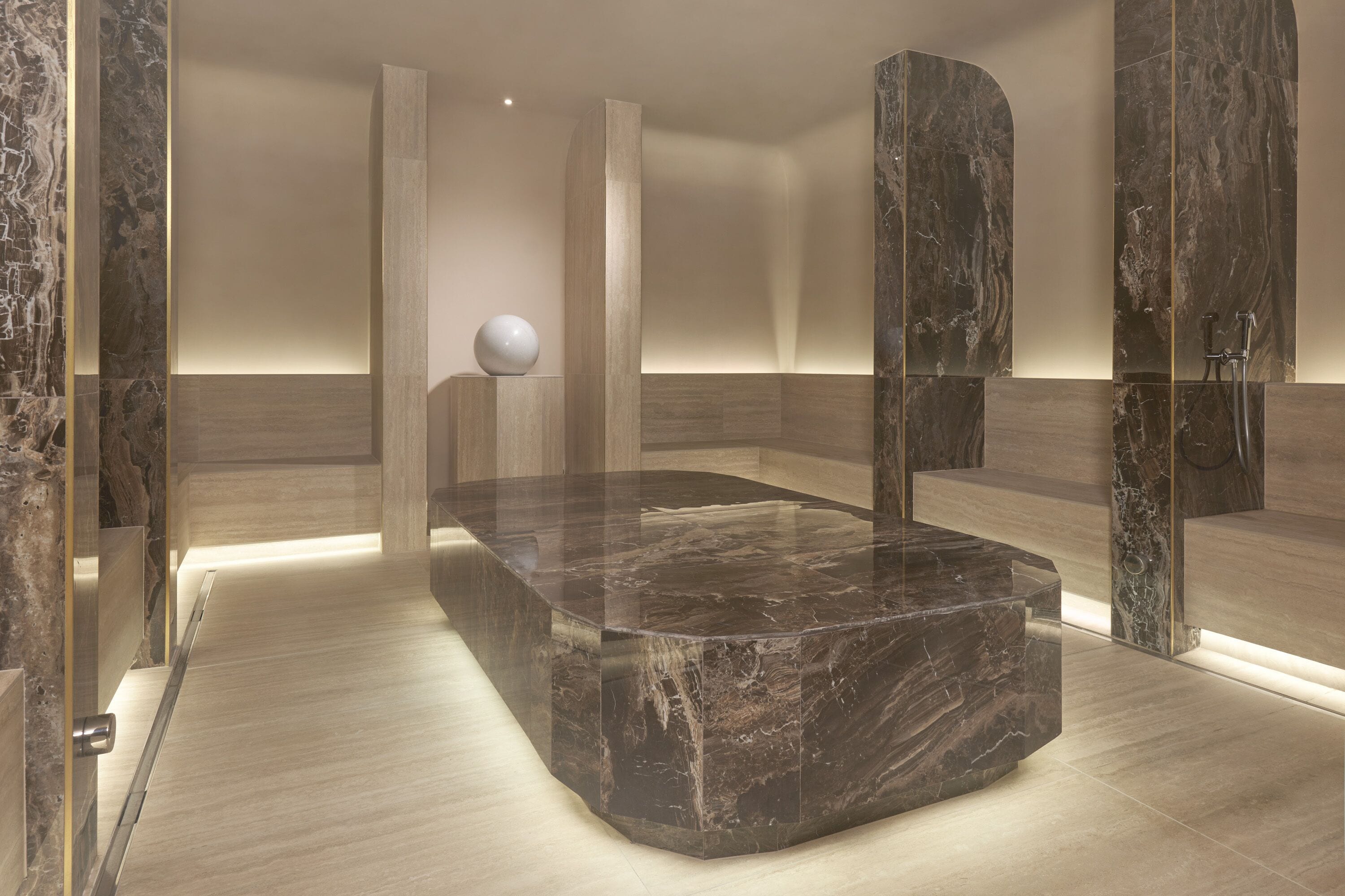 A modern bathroom with a marble sink, a standalone mirror, and a shower area.