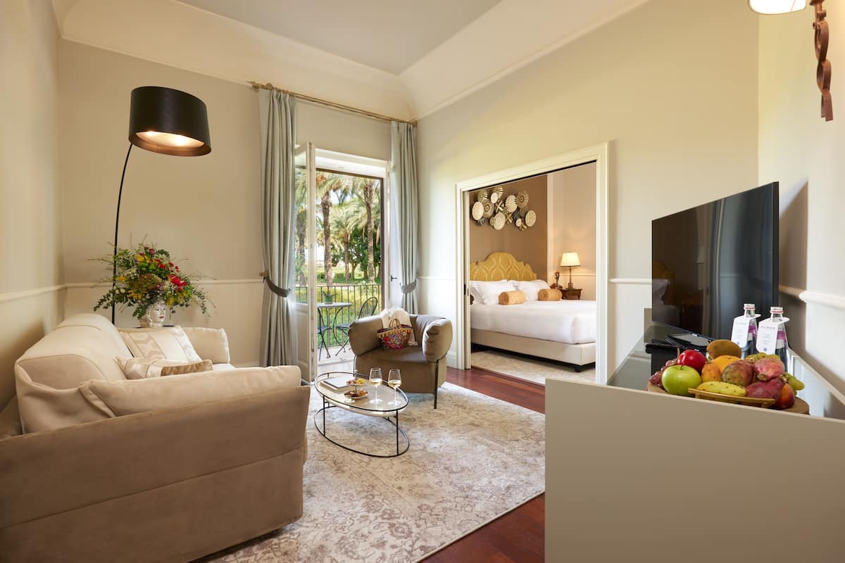 Una sala de estar con sofá, mesa de centro y televisor. Cuenta con una zona de comedor con mesa y sillas, y un área de cocina con frutero.