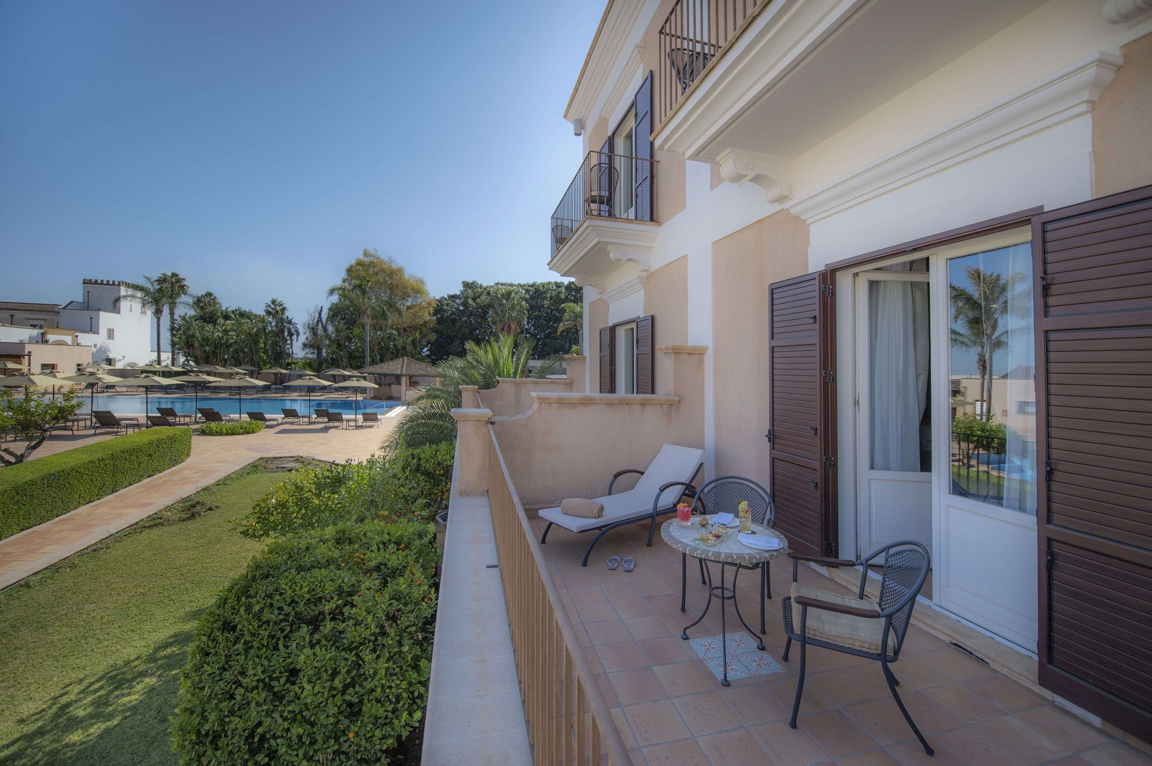 A balcony with outdoor seating, a pool, and a view of the surrounding area.