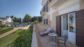 A balcony with outdoor seating, a pool, and a view of the surrounding area.