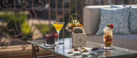 A glass table with drinks and snacks on a balcony.