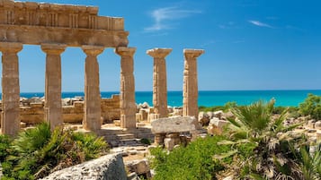 Ancient ruins with columns and a view of the sea.