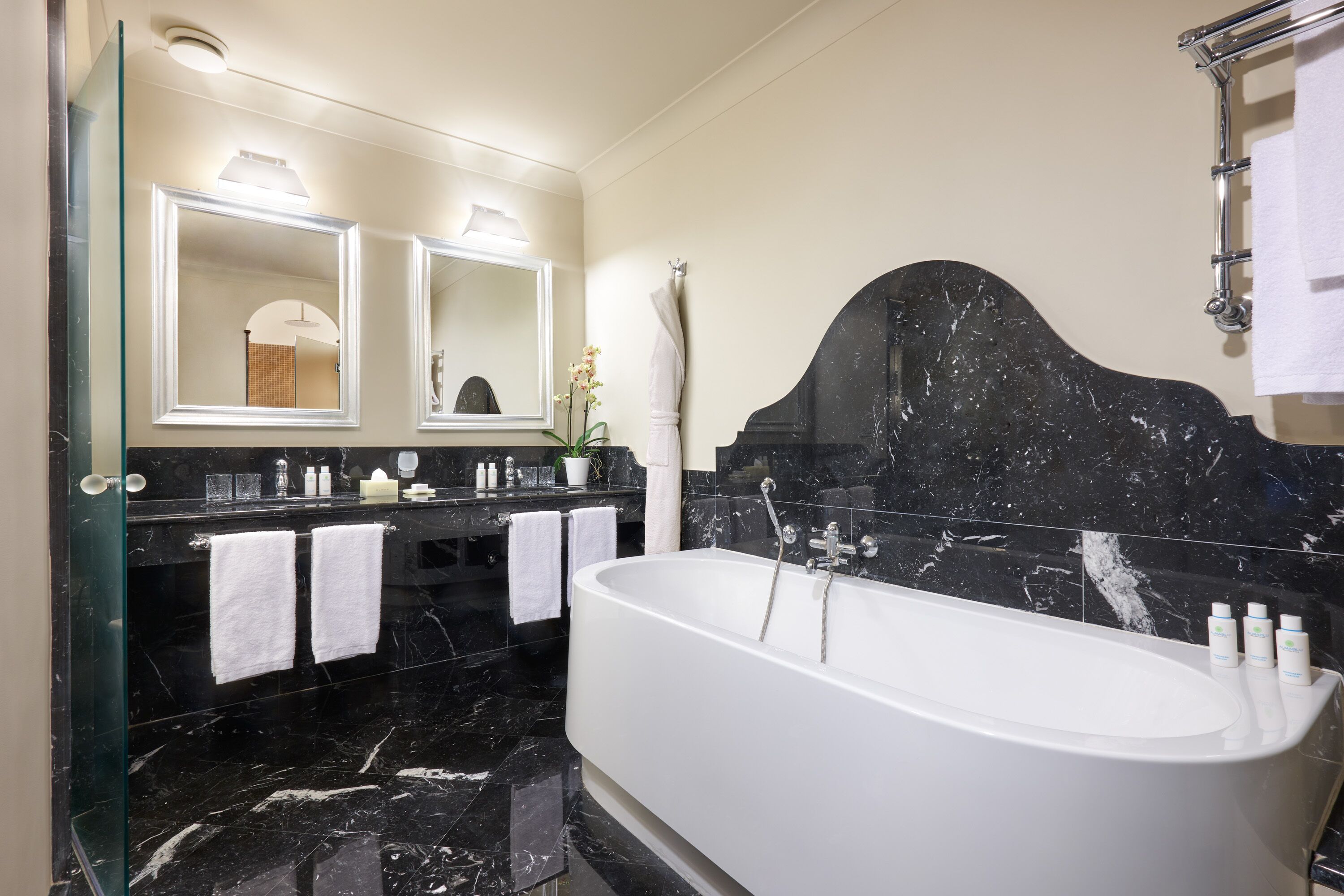 Une salle de bain moderne avec une baignoire sur pieds, des comptoirs en marbre et deux grands miroirs au-dessus du lavabo.