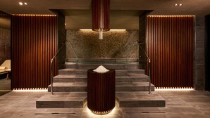 A modern lobby with a central staircase, wooden paneling, and a unique illuminated column. - Almar Giardino di Costanza Mazara del Vallo Resort & Spa (Mazara del Vallo)