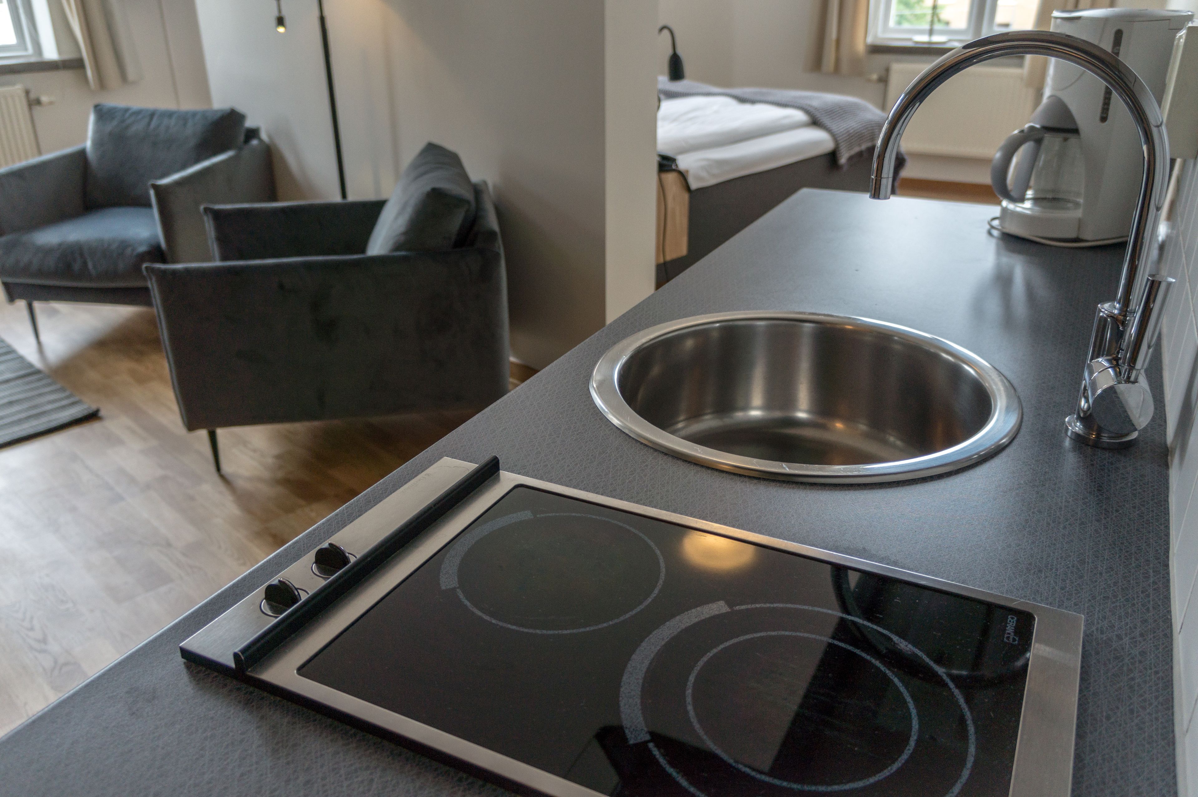 Una cucina moderna con lavello in acciaio inossidabile, piano cottura integrato e piano di lavoro scuro.