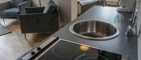 Una cucina moderna con lavello in acciaio inossidabile, piano cottura integrato e piano di lavoro scuro.