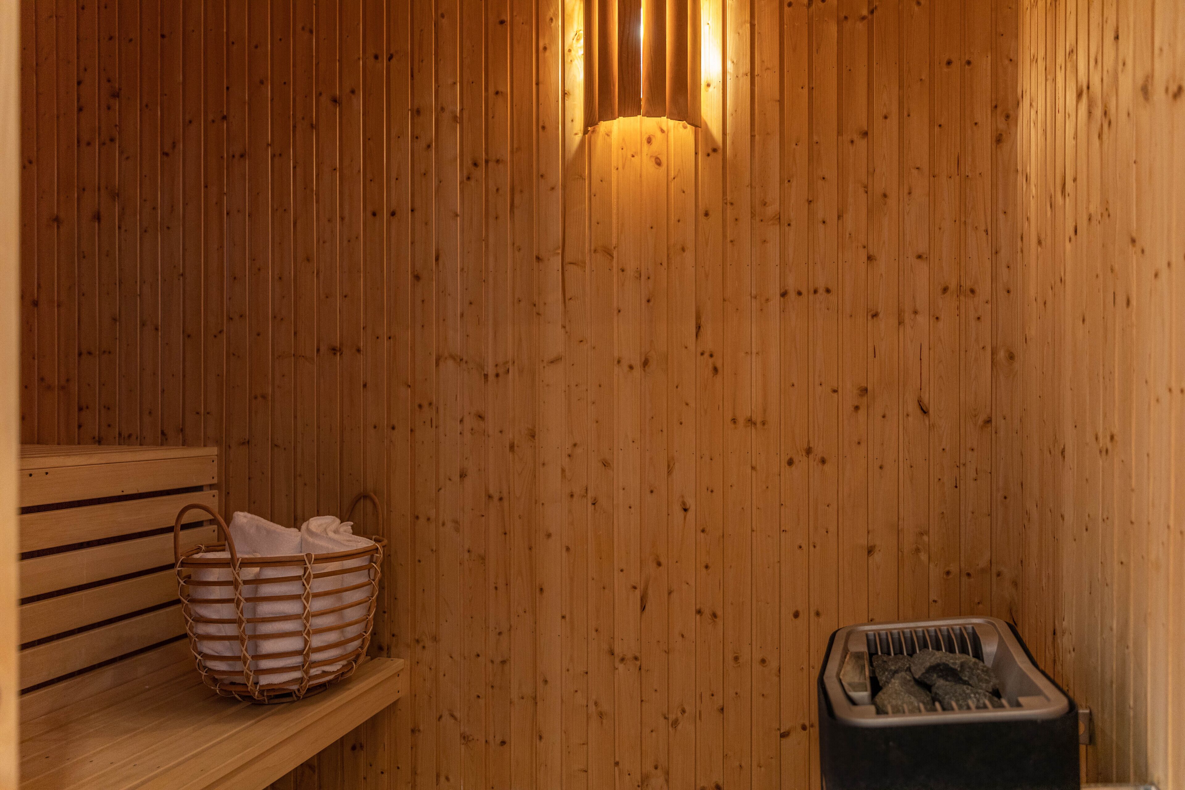 Una sauna de madera con un banco, una cesta y un calentador.