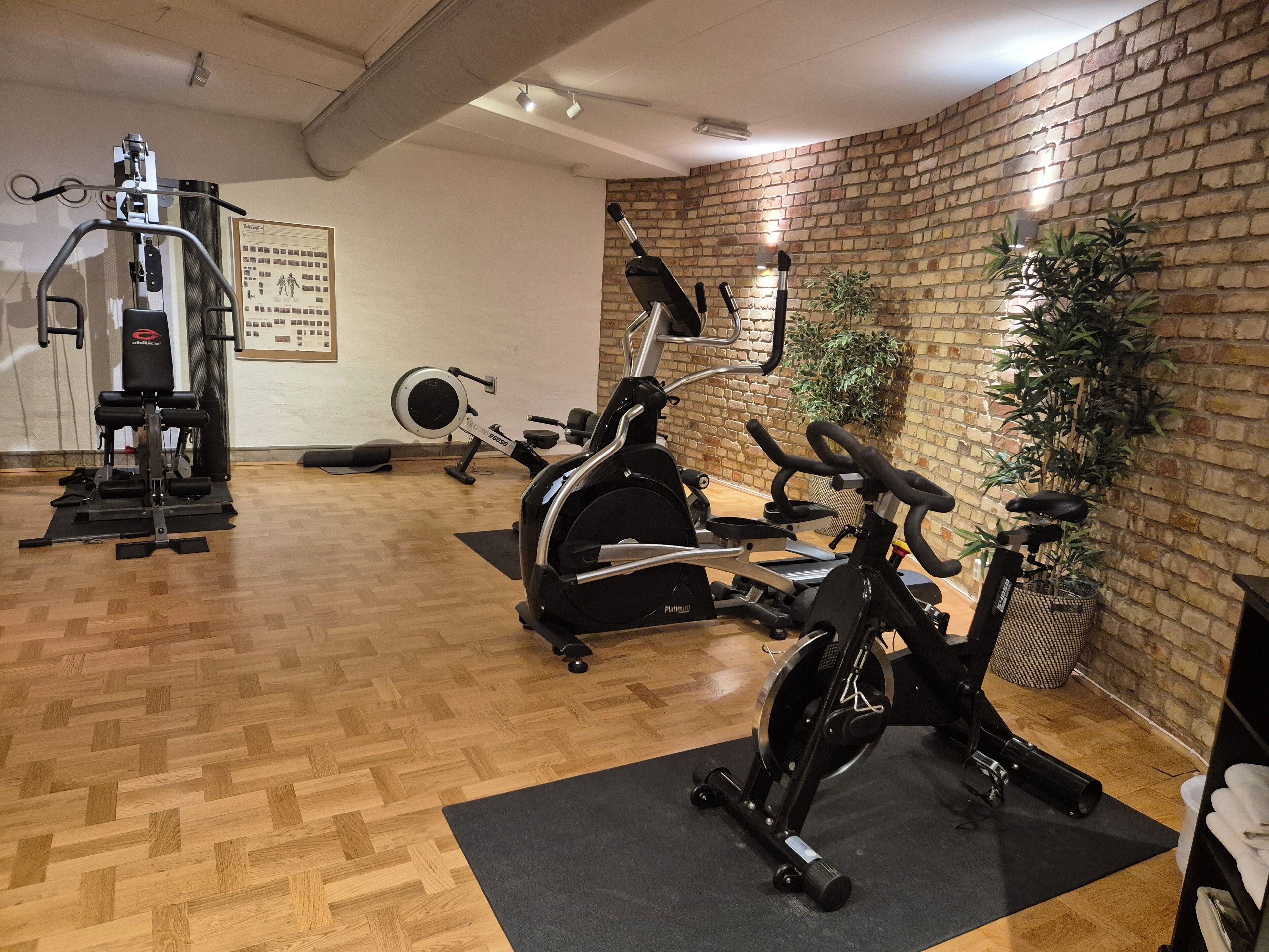 A gym with exercise equipment, wooden flooring, and brick walls.