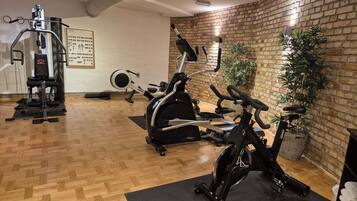 A gym with exercise equipment, wooden flooring, and brick walls.