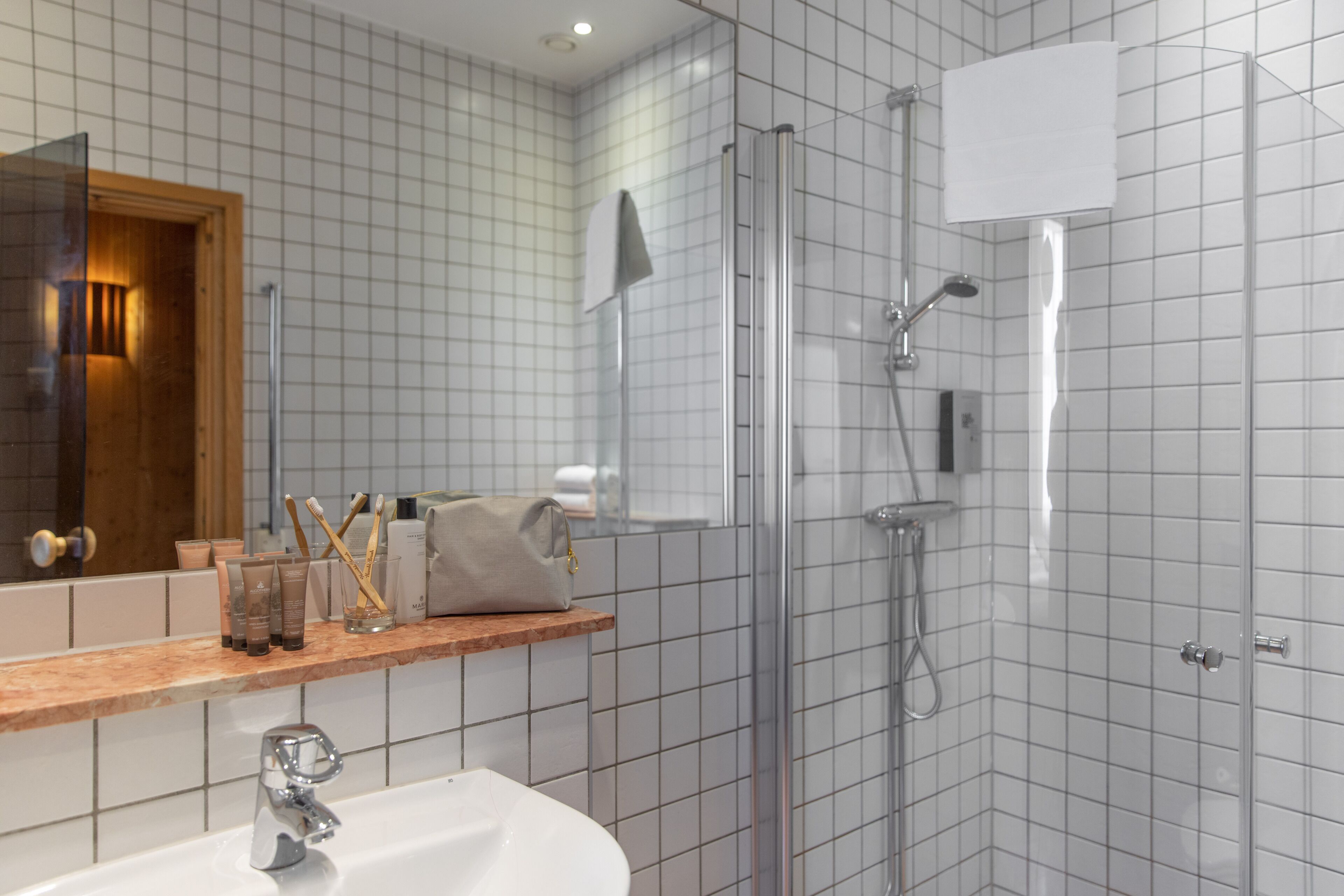 Un baño moderno con ducha de vidrio, lavamanos y espejo.
