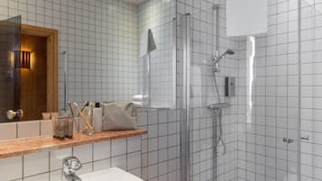 Uma casa de banho moderna com chuveiro de vidro, lavatório e espelho.