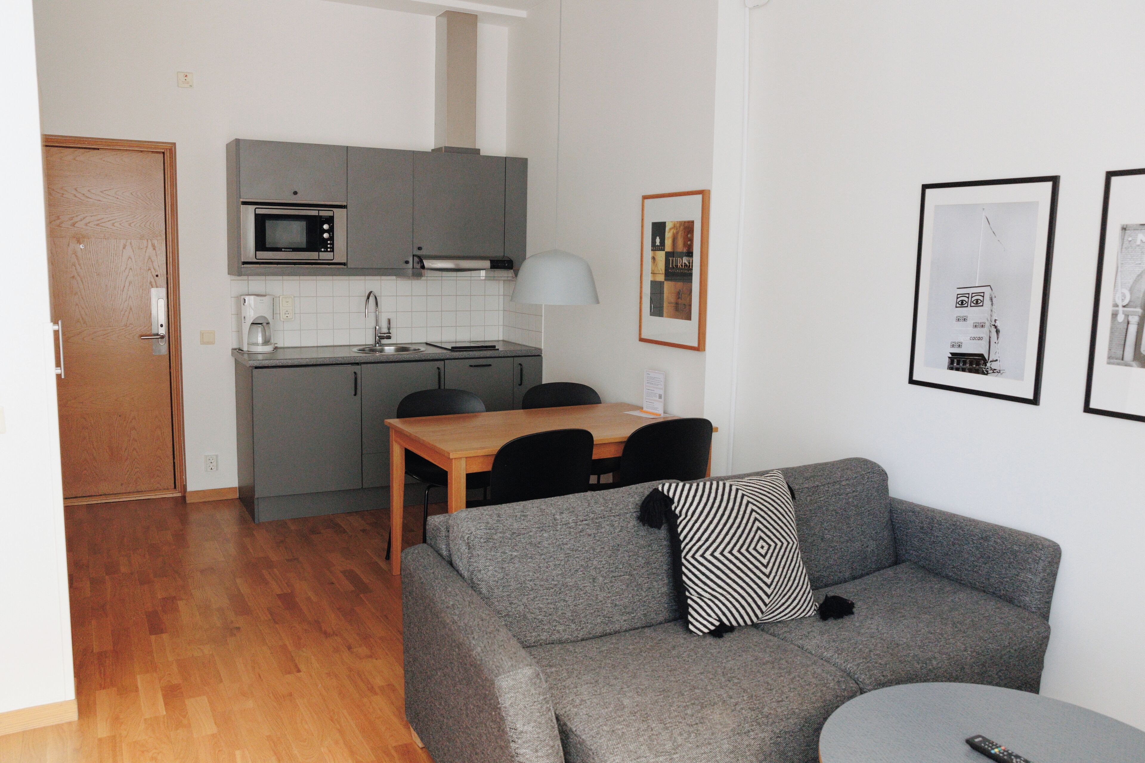 A compact living space with a kitchenette, a dining area, and a seating area with a sofa and a round table.