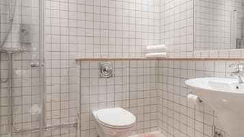 Un baño con cabina de ducha de vidrio, un inodoro blanco y un lavabo con espejo.