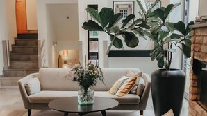A modern living room with a sofa, coffee table, and potted plants. - The More Hotel Mazetti (Malmö)