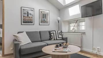 A modern living room with a grey sofa, a round coffee table, and two framed pictures on the wall.