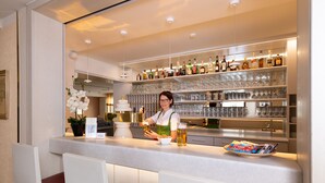 A bar area with a bartender, shelves of liquor bottles, and glasses. - Huberhof (Allershausen)