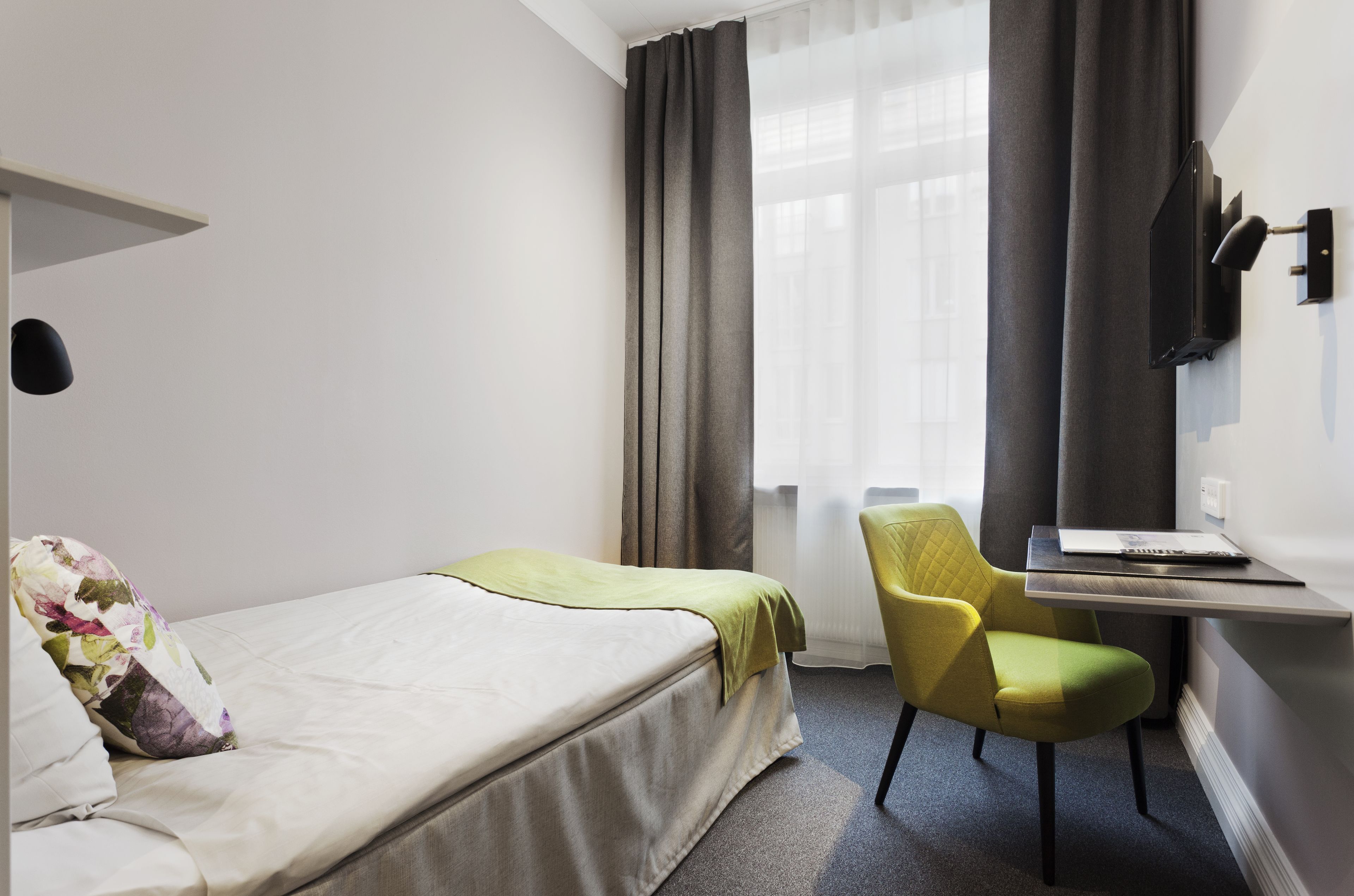 Una habitación de hotel con cama, escritorio, silla y televisión.