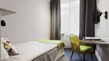A hotel room with a bed, a desk, a chair, and a TV.