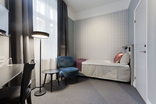 A compact hotel room with a bed, a desk, and a chair. - Hotel Örebro (Örebro)