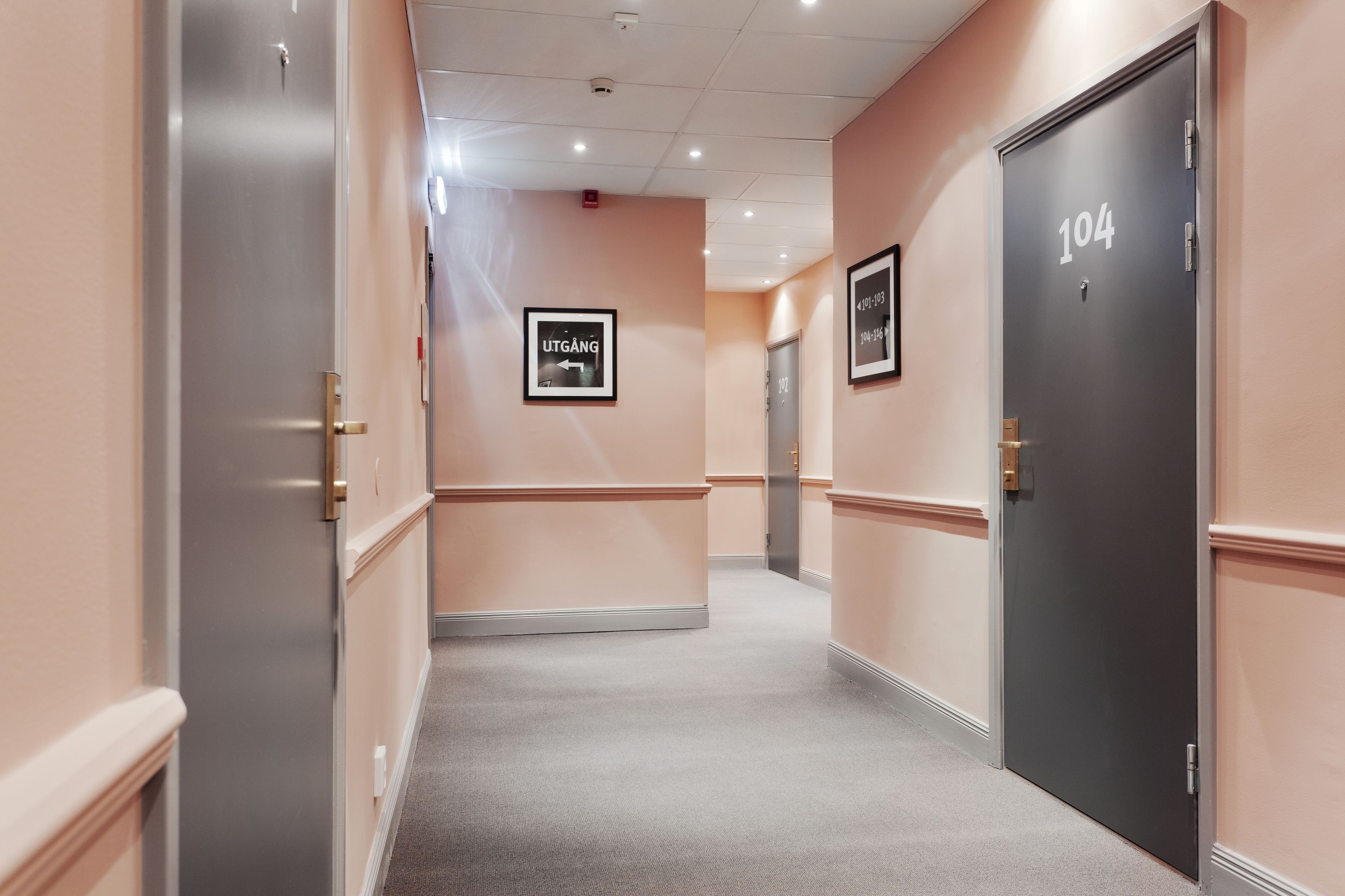 A hallway with doors numbered 104 and 105, a framed sign reading "UTGANG," and a carpeted floor.