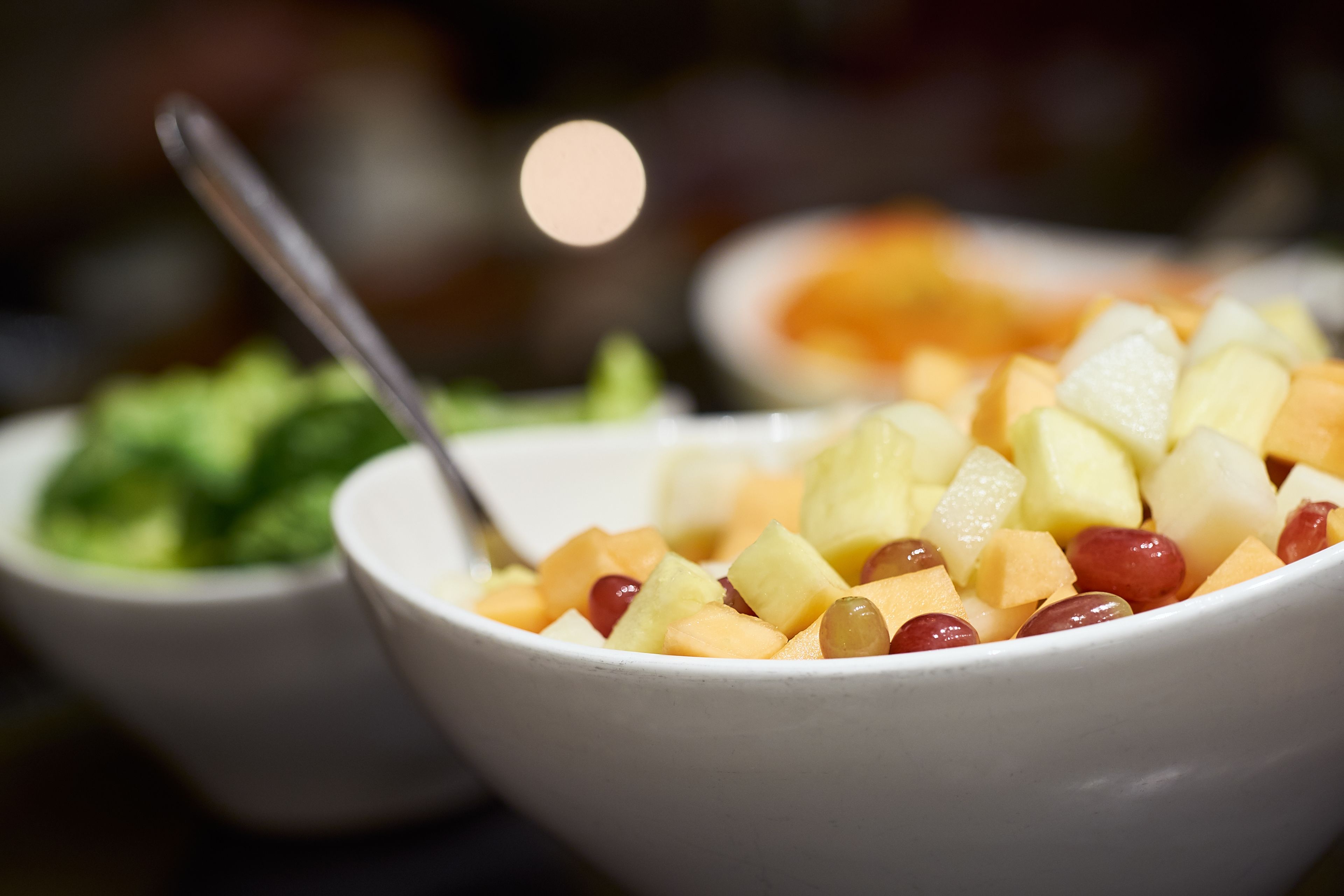 A bowl of fruit salad with a spoon.