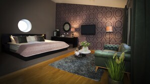 A modern bedroom with a bed, bedside table, TV, and a green armchair.