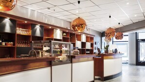 A modern bar area with wooden shelves, a refrigerated display, and hanging spherical light fixtures.