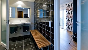 A modern bathroom with a bench, a large mirror, and a tiled floor.