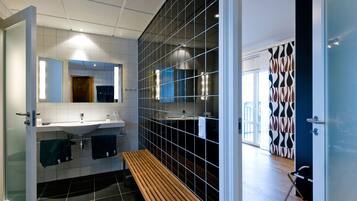 Un baño moderno con un banco, un espejo grande y piso de baldosas.