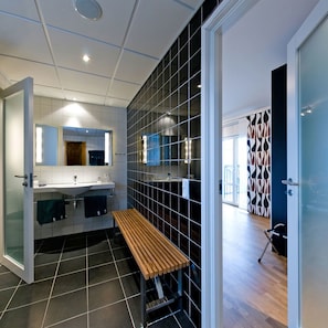 A modern bathroom with a bench, a large mirror, and a tiled floor.