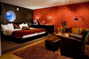 A modern bedroom with a bed, a round window, a desk, a sofa, and a coffee table. - Hotel Örebro (Örebro)