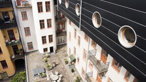 A courtyard with outdoor seating, a building with circular windows, and a rooftop with satellite dishes.