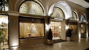 A hotel entrance with large arched windows, a visible reception area, and a tiled floor. - Athens Atrium Hotel and Suites (Athens)