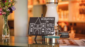 A welcome sign at a hotel reception area with a clear glass vase of flowers to the left.