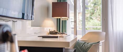 A modern room with a desk, chair, lamp, and a view through a glass door.