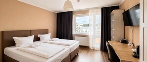 A hotel room with two beds, a desk, a chair, a TV, and a window with curtains. - City-Hotel Frankfurt (Frankfurt)